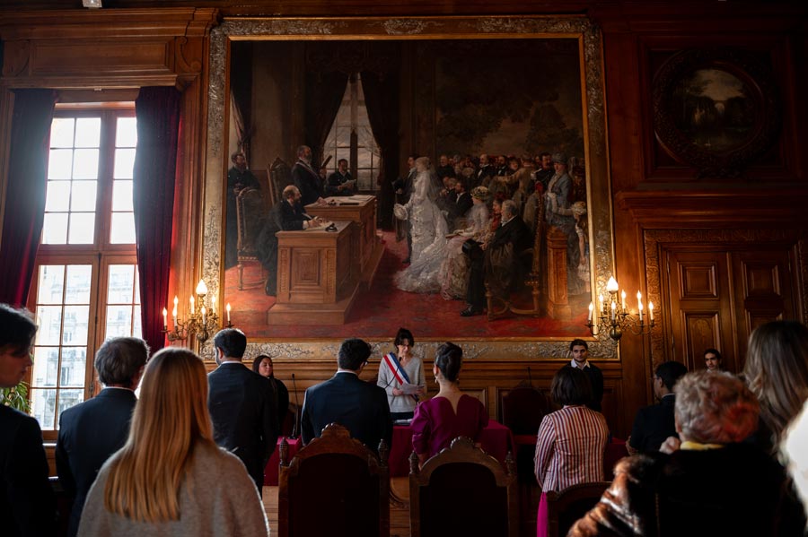 A couple who are getting married in a French town hall where we see the mayor officiating